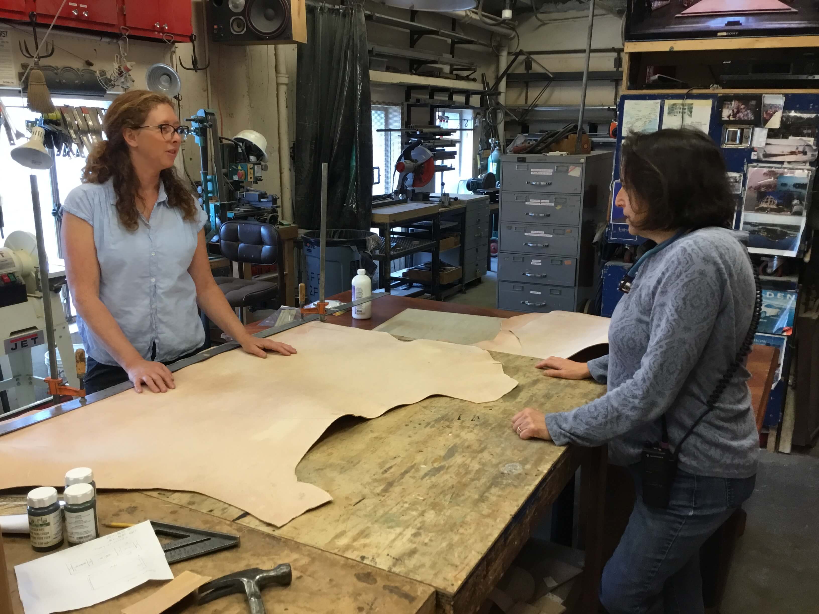 Sarah Shores, in conversation with Properties Master, Lori Harrison, talking about the leather before it is cut for Scarpia’s desk (and the to-be-worked-on desk).