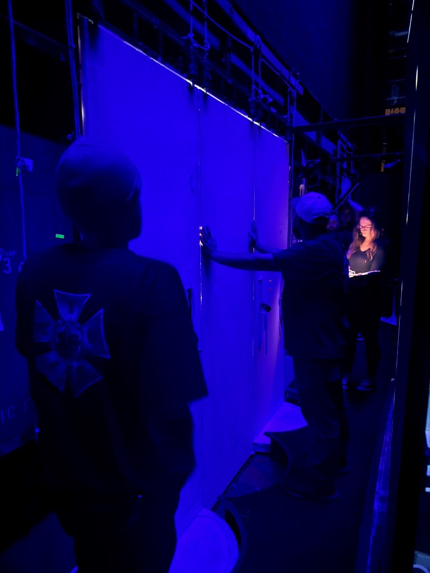 Collette Berg (assistant stage manager), cueing the door action, and members of the carpentry crew operating the doors