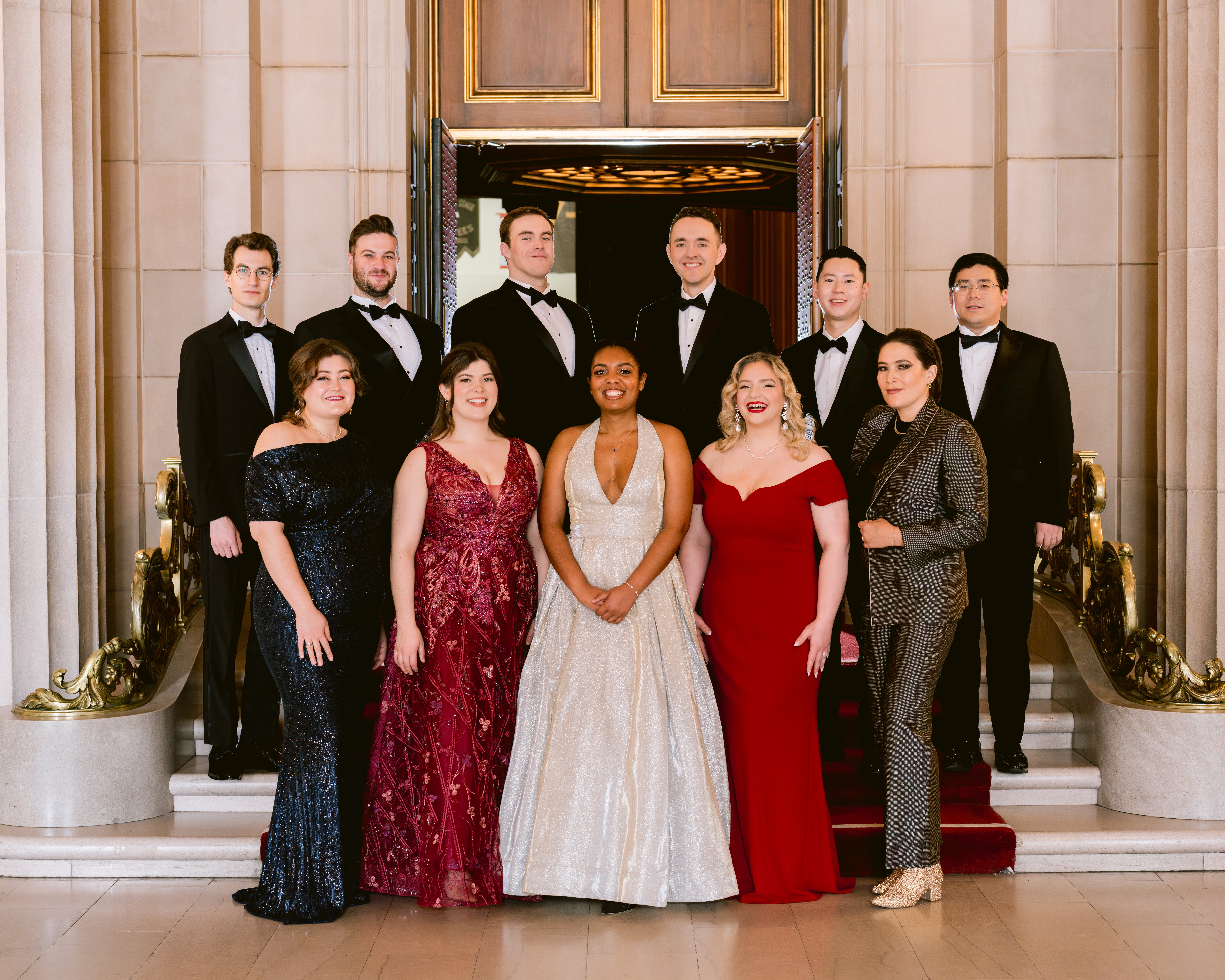 Group photo of individuals standing on stage in fancy attire