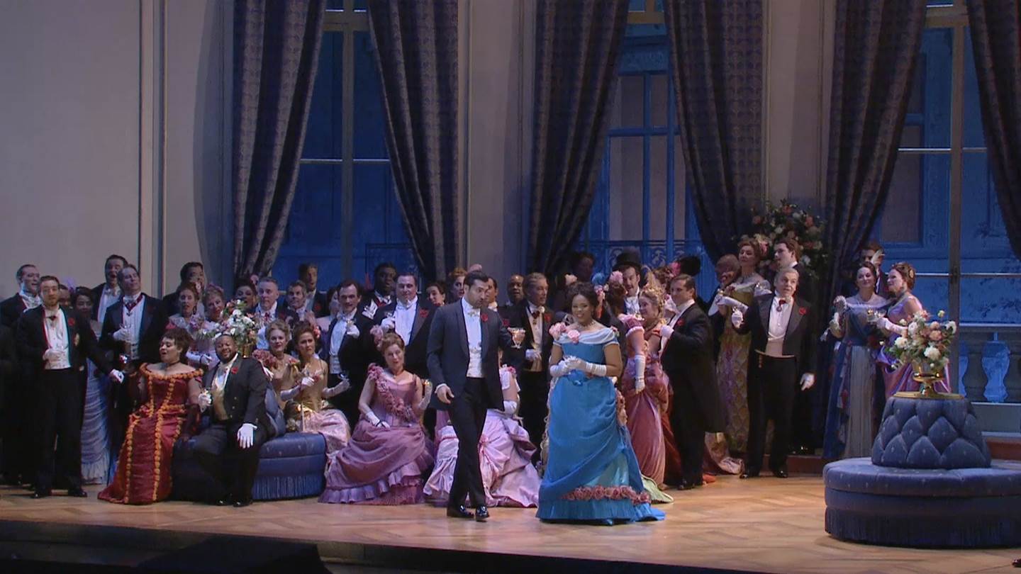 Alfredo and Violetta in a ballroom with several guests watching