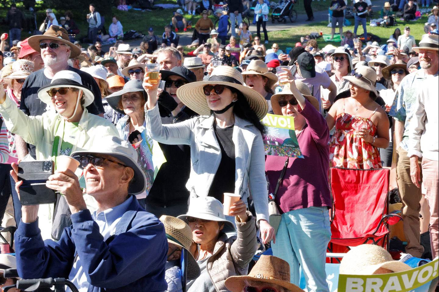 Attendees wearing sun hats and raising their glasses
